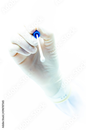 Doctor's hand with sterile gloves holding PCR test for covid-19 pointing at camera tip out of focus, white background