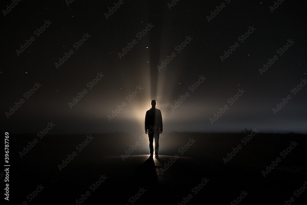 backlighting of a man in the dark of a foggy night and a light behind the model
