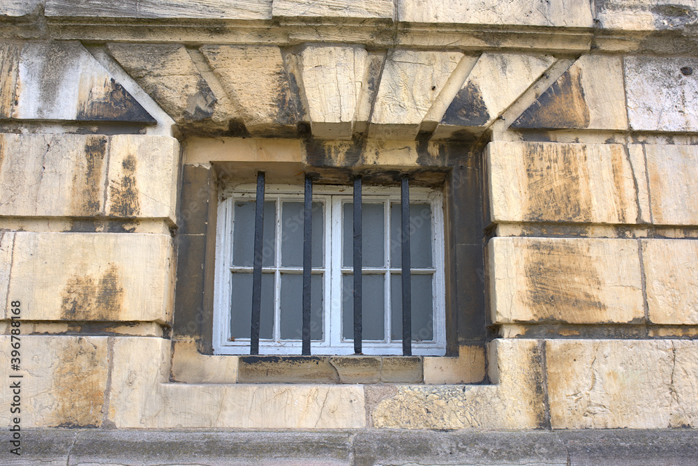 a barred window of a dirty stone wall