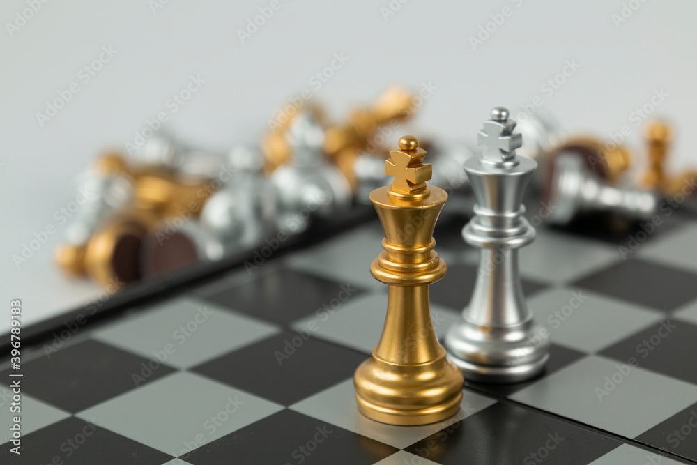 Golden and Silver chess surrounded by a number of fallen chess pieces, business strategy, chess battle, victory, success, teamwork concept. Chess on a chessboard. Chess board game. Golden and Silver chess surrounded by a number of fallen chess pieces, business strategy, chess battle, victory, success, teamwork concept. Chess on a chessboard. Chess board game.