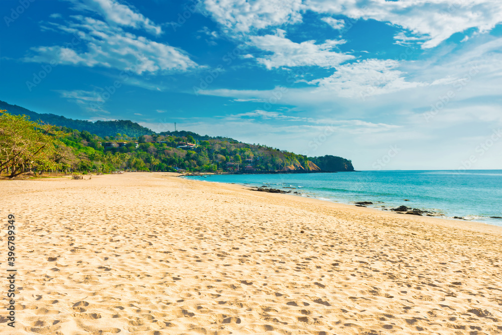 Tropical beach with white sand and green mountain near blue sea in Koh Lanta island, Thailand
