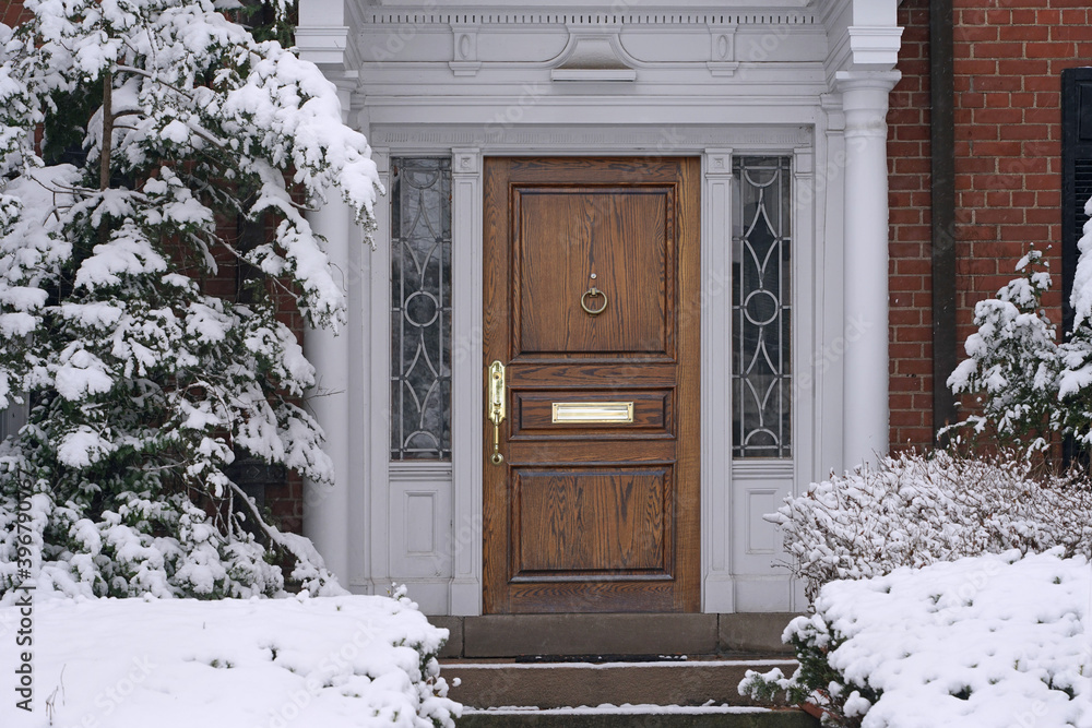 front door with elegant wood grain, with snow covered house entrance  фотография Stock | Adobe Stock