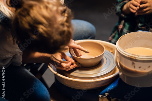 a young mother teaches her son the family pottery craft in a workshop