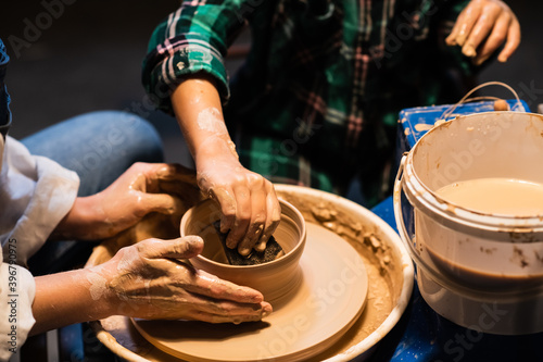 the process of modeling clay dishes on a potter's wheel, the hands of a young girl and a child