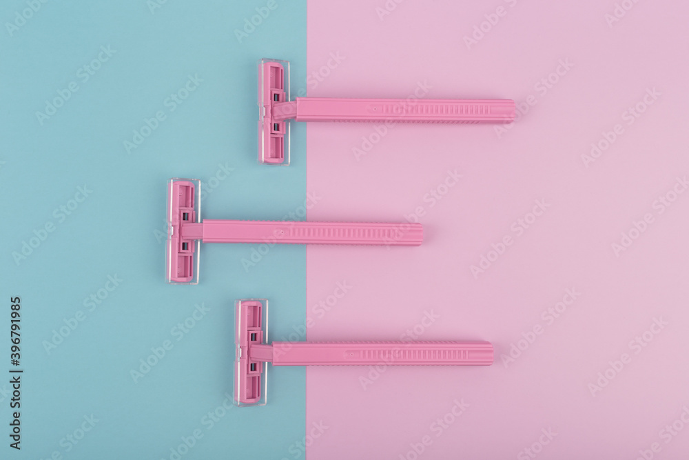Flat lay with three pink razors on blue and pink background. Minimalistic concept of shaving and skin care Flat lay with three pink razors on blue and pink background. Minimalistic concept of shaving and skin care