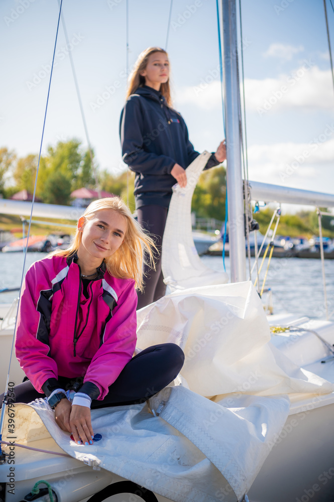 Two girls decided to spend a weekend on the river, preparing the yacht to go out on the water.