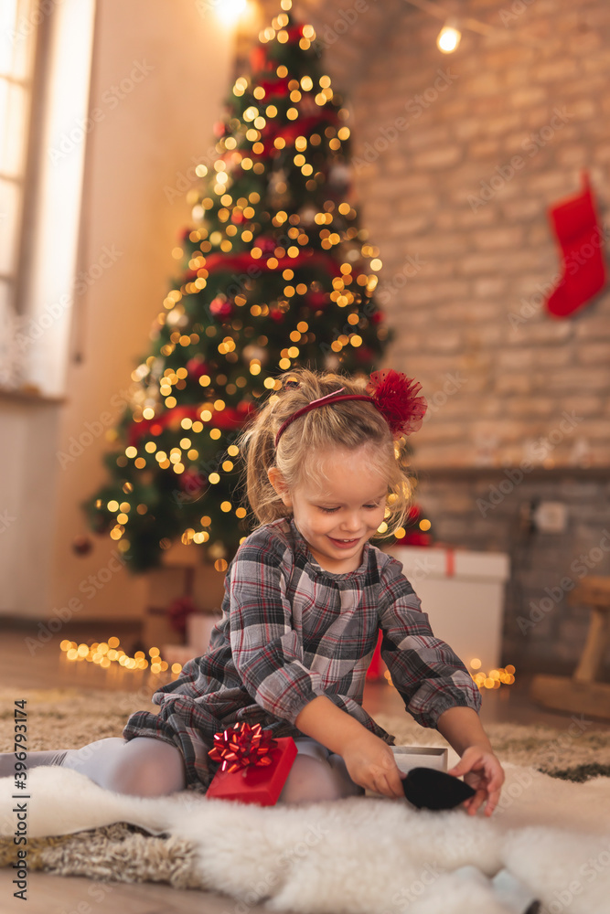 Little girl playing by the Christmas tree Little girl playing by the Christmas tree