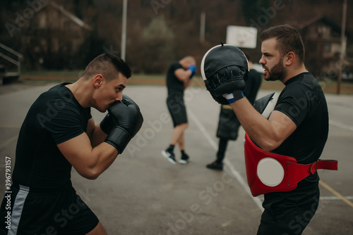 Two athletic young men boxing . Men training outdoors . Training kickboxing.Two males boxing outdoors. Sparring training box outside sport concept.