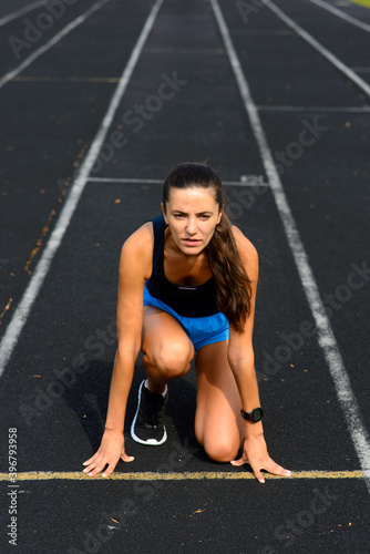 Healthy young woman warming up stretching her arms and looking away in the stadium outdoor.