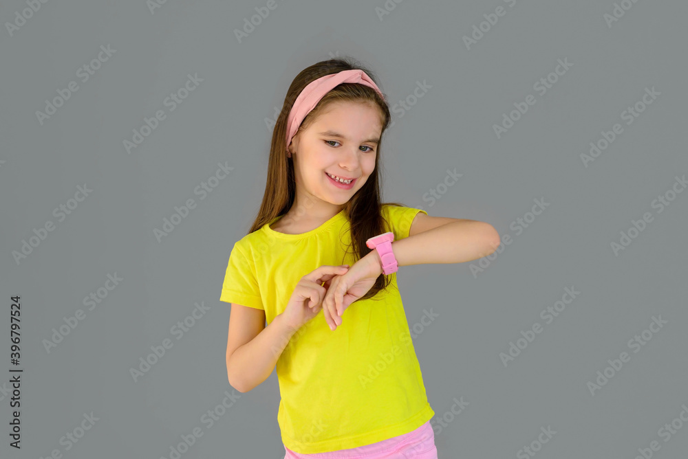 Cute girl and pink children's smart watch isolated on gray background. Protection and control. Cute girl and pink children's smart watch isolated on gray background. Protection and control.