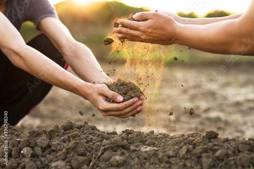 Expert hand of farmer pouring good soil to a hand of young farmer at garden or farm.