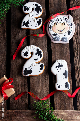Gingerbread cookies in the form of numbers 2021, Gingerbread cow as symbol 2021 on wooden background. Christmas and Happy New Year 
