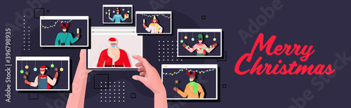 human hands using tablet pc santa in mask discussing with mix race people during video call new year and christmas holidays celebration online communication self isolation concept horizontal vector