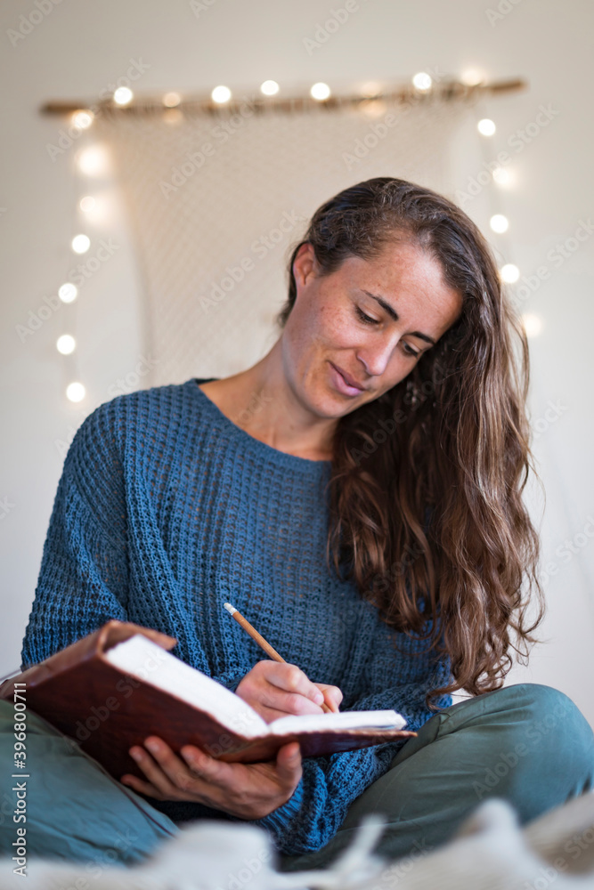 Woman in blue sweater making notes in her journal Woman in blue sweater making notes in her journal