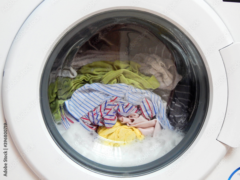 Foamy washing machine with different clothes. Foamy washing machine with different clothes.