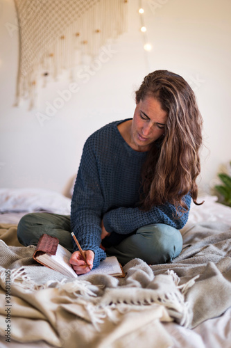Woman journaling whilst sat on bed