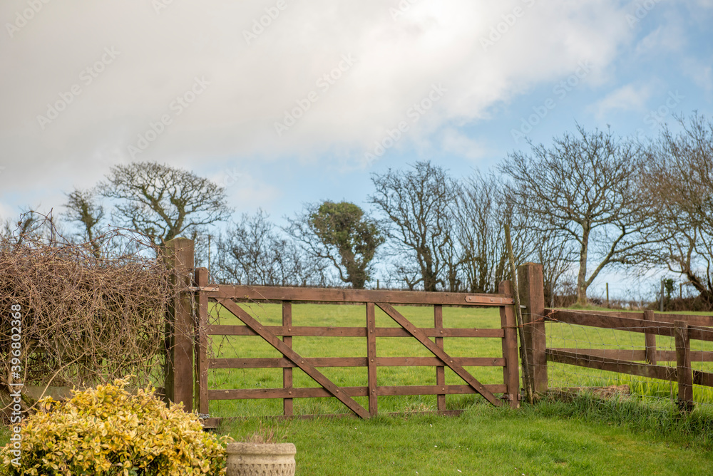 Scenic image of a wooden gated fence in a green field in Autumn