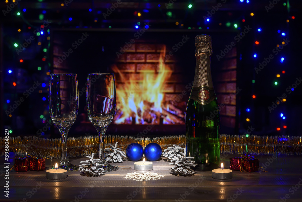 Two glasses with wine on the table against the background of the fireplace. Christmas New Year decorations, fireplace. Fire, wood. Two glasses with wine on the table against the background of the fireplace. Christmas New Year decorations, fireplace. Fire, wood.