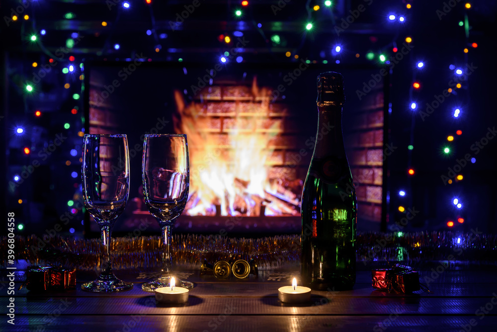 Two glasses with wine on the table against the background of the fireplace. Christmas New Year decorations, fireplace. Fire, wood.