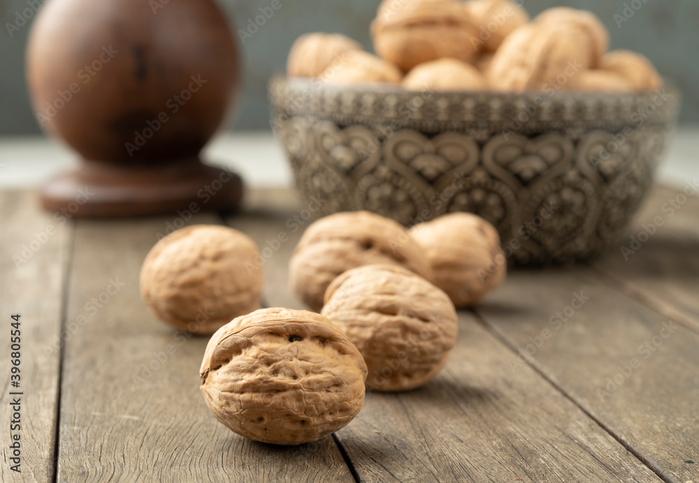 Walnuts over a wooden table and into a bowl Walnuts over a wooden table and into a bowl