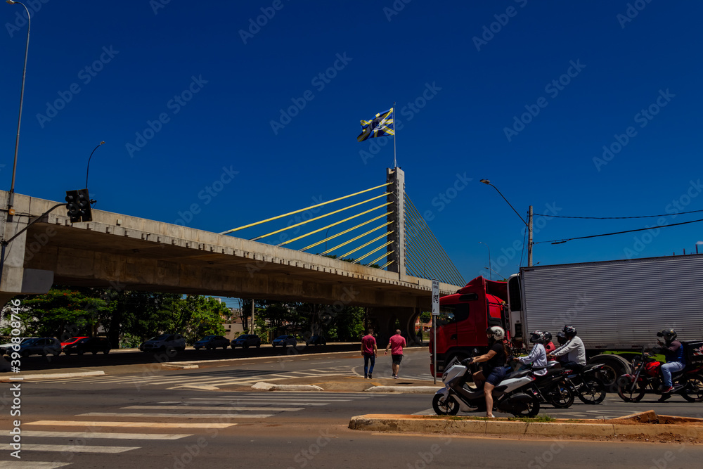Fototapeta premium Viaduto Estaiado na cidade de Anápolis em Goiás. Viaduto com uma bandeira da cidade de Anápolis com céu azul ao fundo.