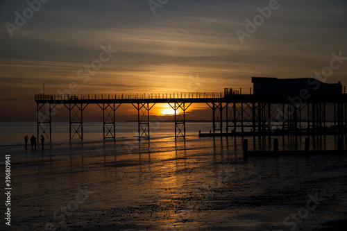 A beautiful moody sunset with reflections in the water and sand be the Pier at Bognor Regis.