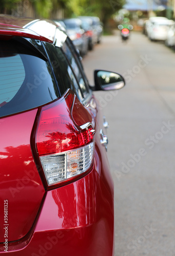 Closeup of rear, back side of red car with other cars parking in outdoor parking area. Vertical view. 
