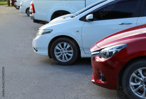 Closeup of front side of red car with  other cars parking in outdoor parking area. © Amphon