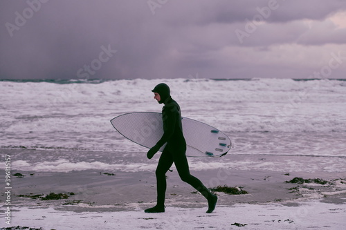 Canvas Print Arctic surfer going by beach after surfing