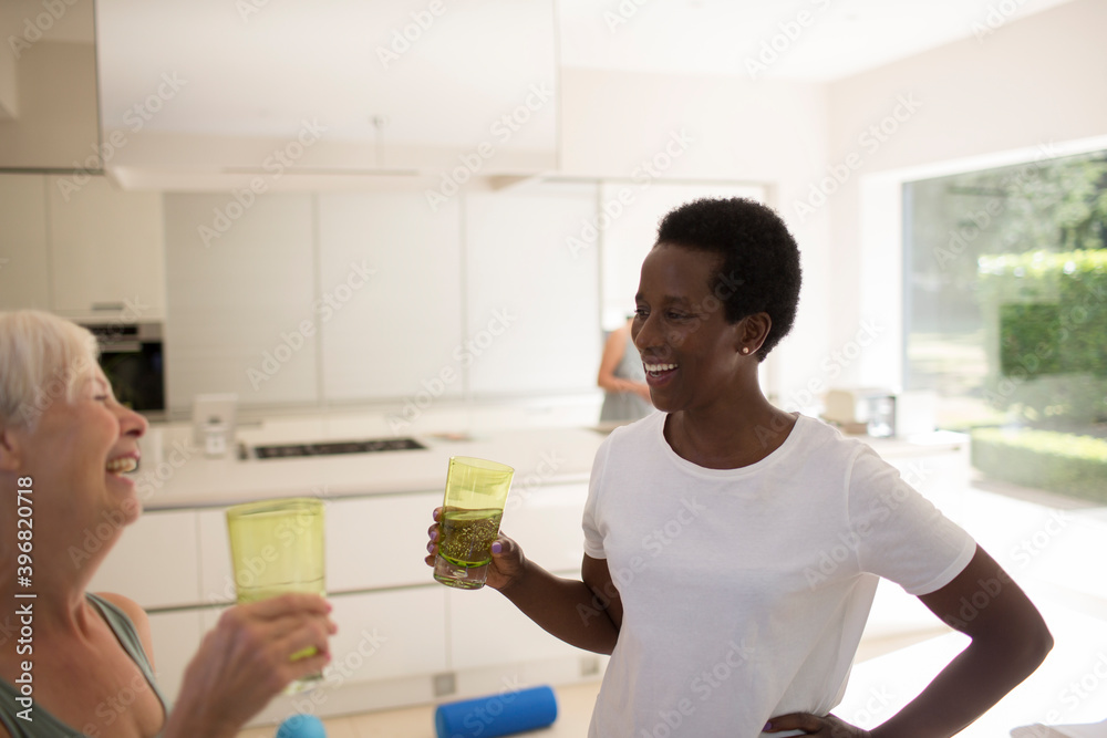 Happy senior women friends drinking water after exercising at home
