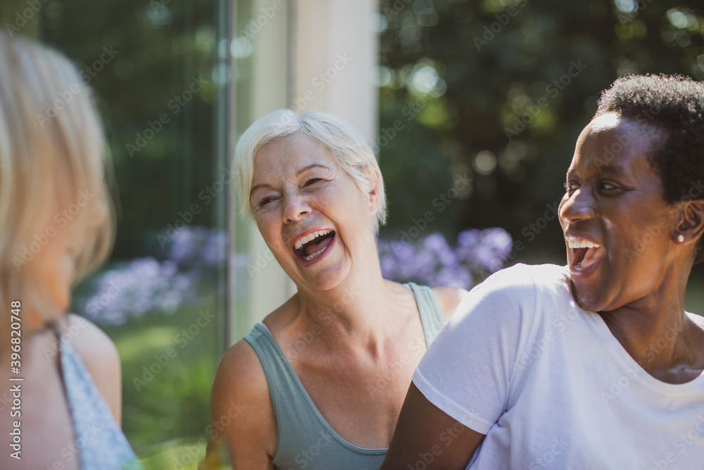 Happy senior women friends laughing on summer patio Happy senior women friends laughing on summer patio