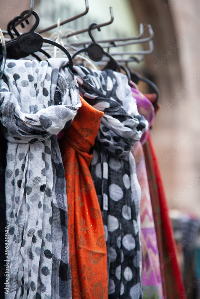 Multicolored fabric scarves, shawls, stoles on a metal rack for street trade in a store