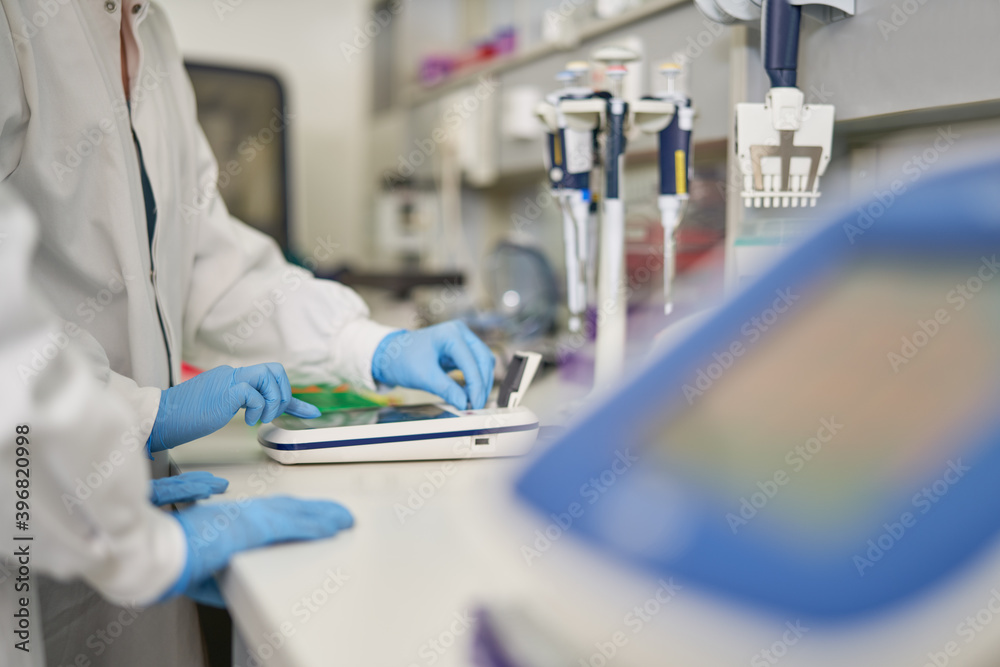 Scientists in rubber gloves using equipment in laboratory Scientists in rubber gloves using equipment in laboratory