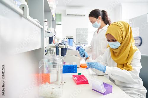 Female scientists in face masks and hijab working in laboratory