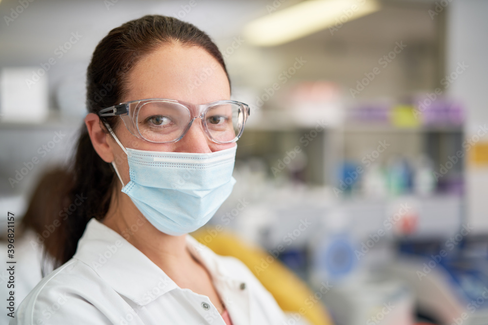 Portrait confident female scientist in face mask in laboratory