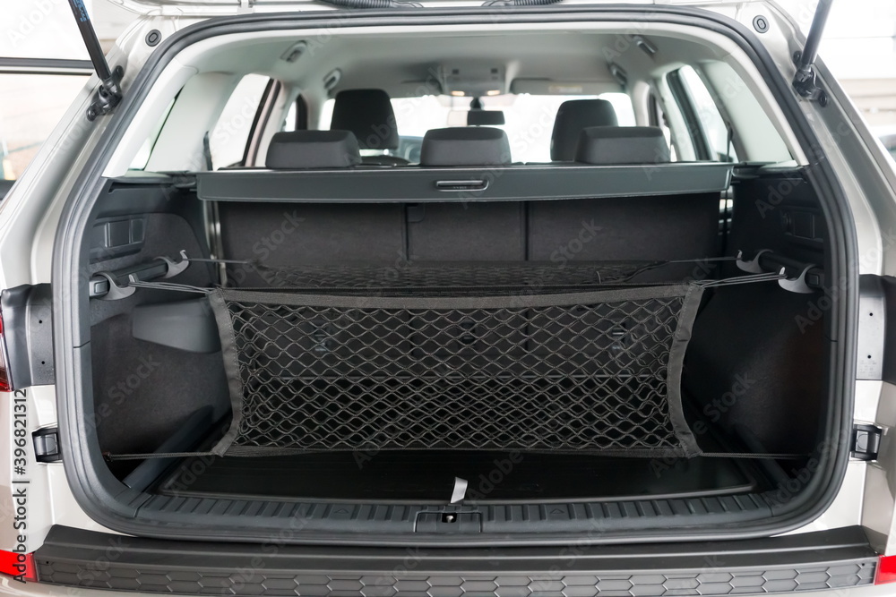 The luggage net for groceries hangs in the open trunk of the car.