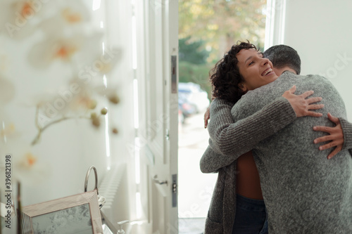 Happy affectionate couple hugging at front door of house