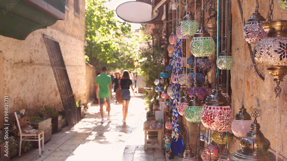 Fototapeta premium Turkish bazaar lamps hanging on the wall. Tourists walking on the street of old town Kaleici, Antalya, Turkey.
