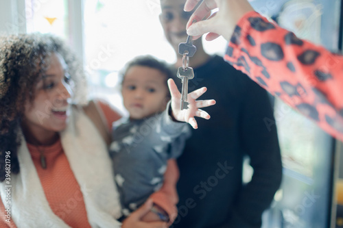 Happy young family receiving new house keys from realtor