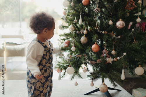 Cute baby girl looking at Christmas tree decorations