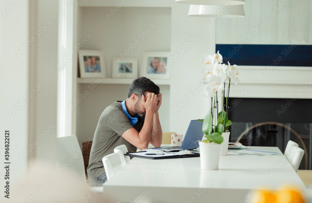 Tired man with head in hands working from home at laptop Tired man with head in hands working from home at laptop