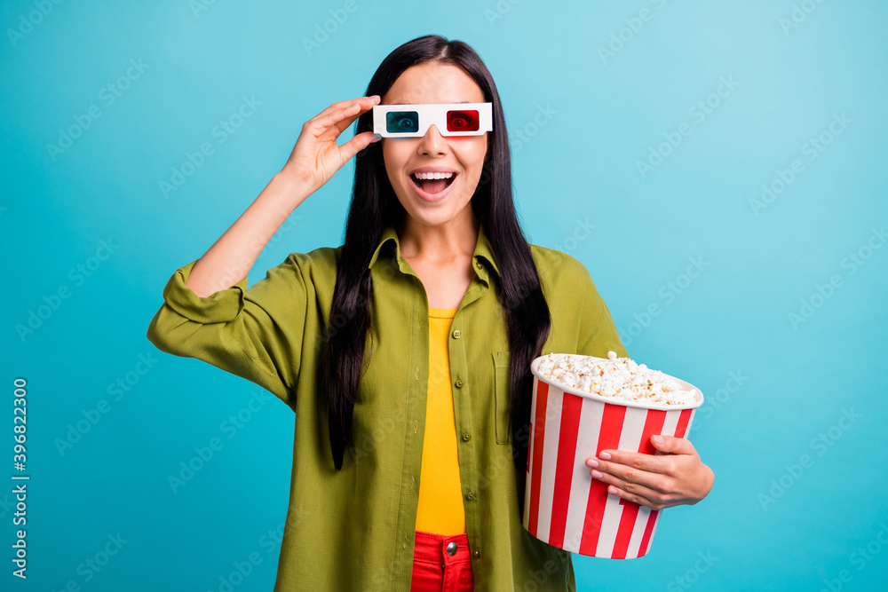 Obraz premium Photo of positive lady hold big paper box popcorn having fun wear 3d glasses green shirt isolated blue color background