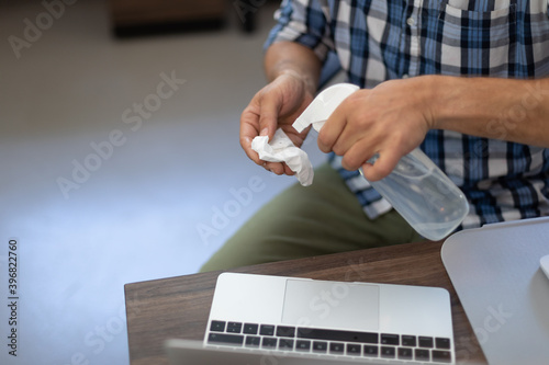 Caucasian man disinfecting his laptop in an office