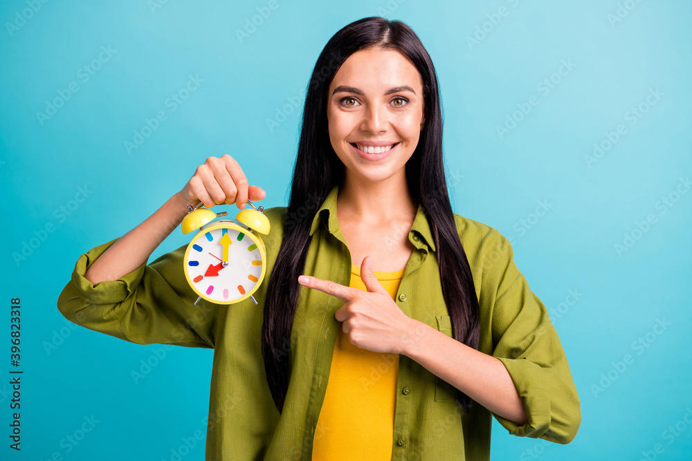 Fototapeta premium Photo of lady hold alarm clock indicate forefinger shiny smile wear green shirt isolated blue color background