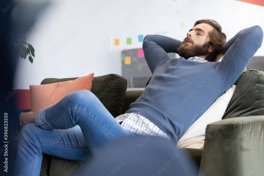 Caucasian businessman sitting on sofa relaxing in creative office