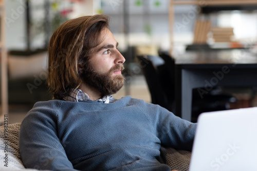 Caucasian businessman using laptop sitting in armchair in creative office