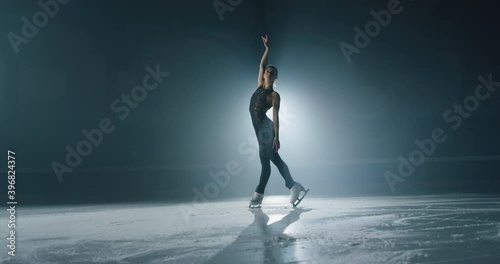 Cinematic shot of young female artistic figure skater is performing a woman's single skating choreography on ice rink before start of a competition. Concept of perfection, precision, freedom, passion.
