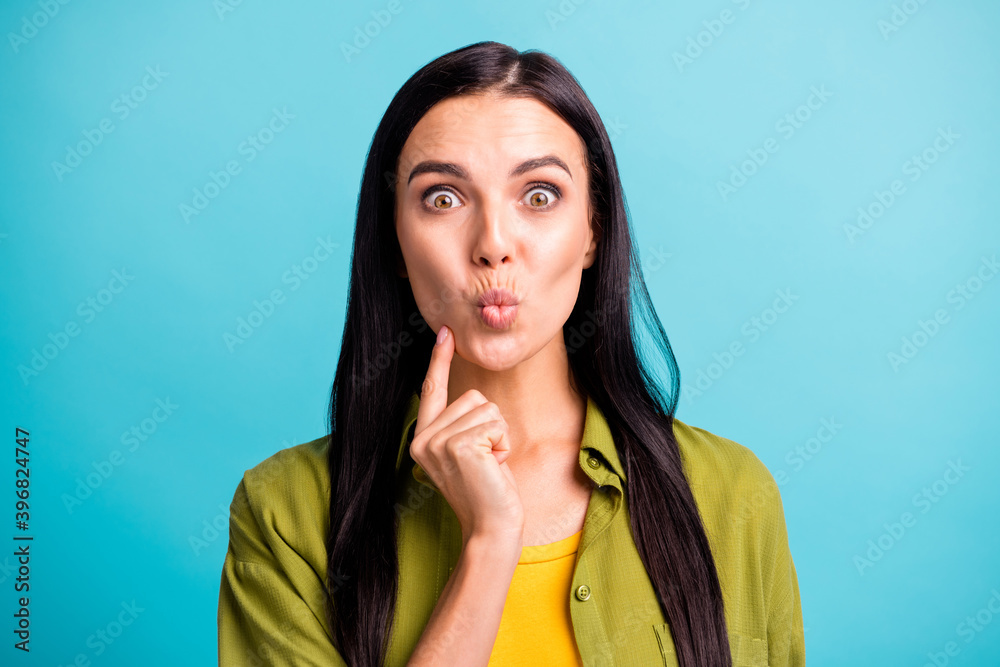 Photo of shocked young girl look camera funny face lips finger cheek wear green shirt isolated blue color background Photo of shocked young girl look camera funny face lips finger cheek wear green shirt isolated blue color background