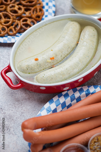 Bowl of weisswurst in bouillon and wiener wurstchen with pretzels and beer, vertical shot, close-up photo