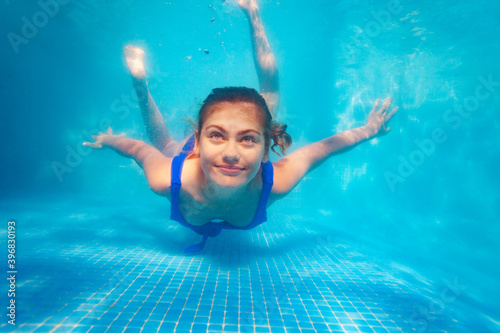 Portrait of the girl swim underwater with confident positive smile in the pool